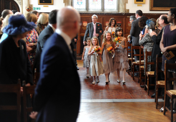 Groom watching the bridesmaids and bride walk down the aisle towards him