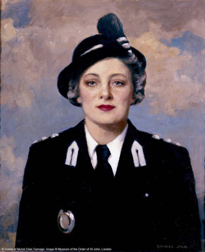 A half length portrait of a lady facing forward, wearing a black and white St John Ambulance uniform, including hat, with a sky with clouds as the background