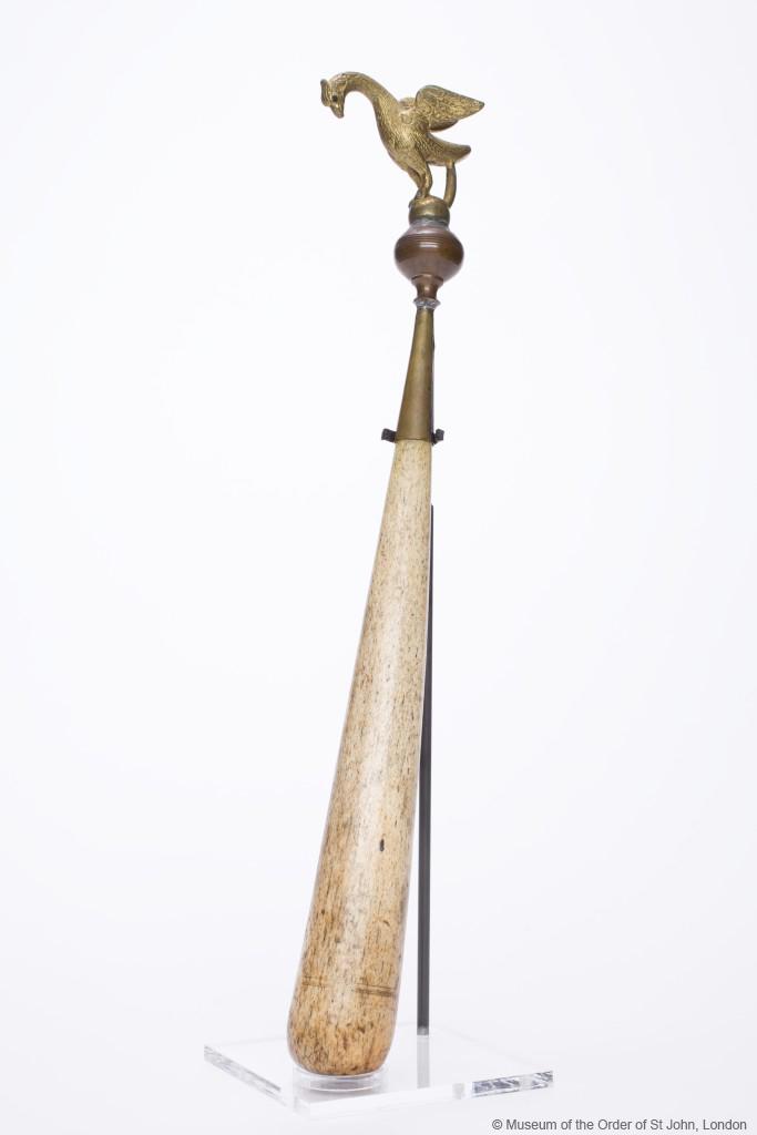 A bone baton with rounded end, with a metal falcon atop a sphere