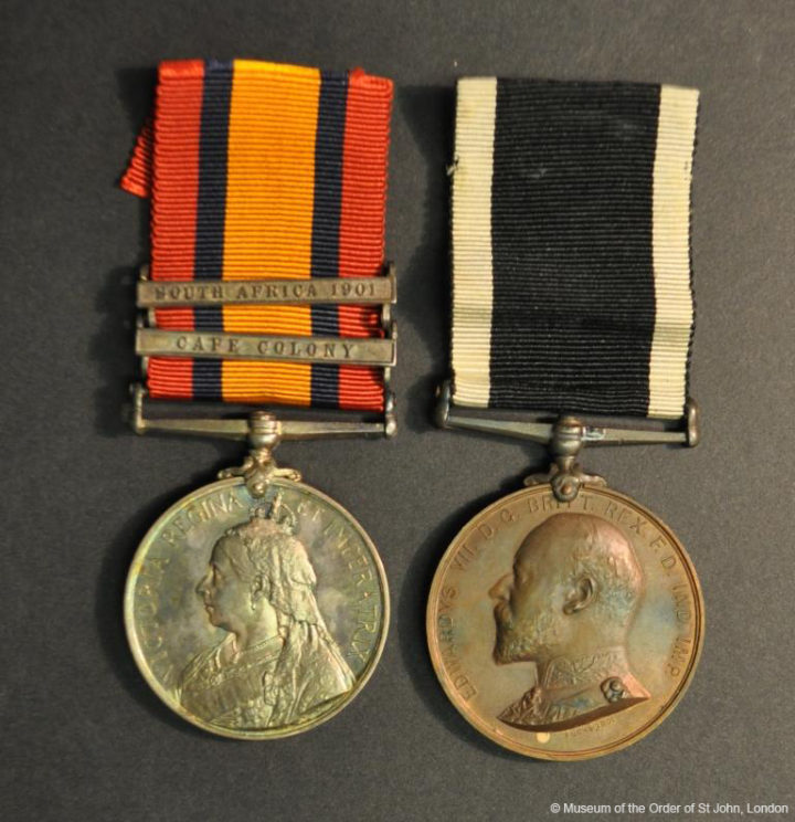 Two medals suspended from ribbons. The first is silver with a profile portrait of Queen Victoria and a red, black and orange ribbon with two clasps reading South Africa 1901 and Cape Colony. The second is bronze and has a profile portrait of Edward VII and a white and black ribbon.