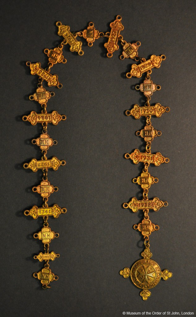 Obverse of bronze medallion, labels and pendants with numbers and names engraved on them, all attached by chain links.