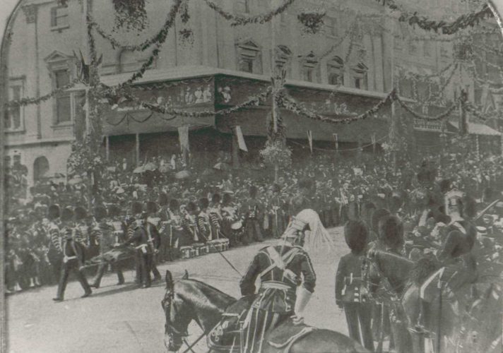 large procession with a man being carried in a stretcher in the corner