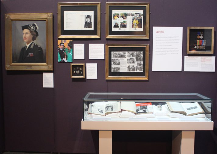 Photograph of an exhibition with several framed items on the wall