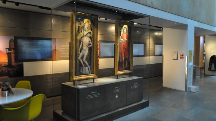 Photograph of a museum gallery with two oil paintings.