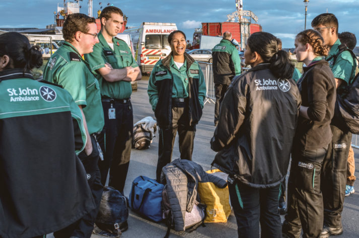 A colour photograph showing a group of male and female Cadets in their black and green Service Delivery Uniform chatting in daylight at the start of the event. 
