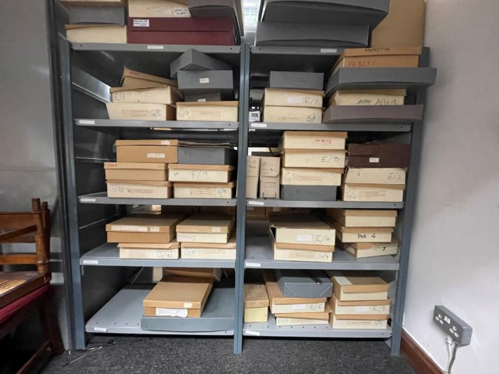 This image shows some racks of metal shelving, with cardboard boxes of various sizes on the shelves.