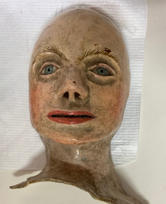 Close up of the replica skin cover for the face of the anatomical model. The skin is white and the eyes are blue and the model has no hair.