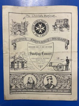 The cover of a booklet accompanying a Smoking Concert. The cover is busy with text and illustrations. In the centre of the page is the Smoking Concert location information, flanked on the left by an illustration of a first aid hut and on the right by a wheeled ambulance litter and an accompanying man. Below, across the length of the bottom of the page, is an illustration of a St John Ambulance Brigade member in 1890, and a member of the Knights Hospitaller in 1090, both surrounded by a motif of leaves. At the top of the page are the words ‘Pro Utilitate Hominum’, and below that, in a row, are three illustrations: on the left is an illustration of St John’s Gate, on the right is an illustration of an early horse-driven ambulance, and in between is the logo of the St John Ambulance Association. Below that are the words ‘St John Ambulance Brigade’.