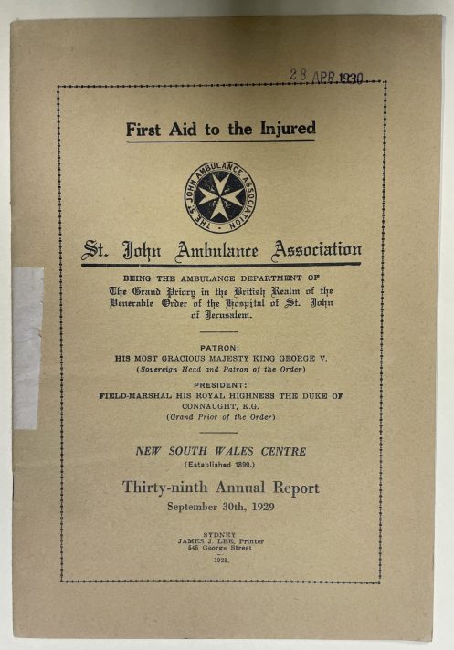 A small off-white booklet is laid flat on a pale piece of cardboard. The booklet is an annual report. The front cover is the only part visible, and it includes a lot of black text which explains the organisation’s name (St John Ambulance Association) and the Centre which the report is from (New South Wales). 